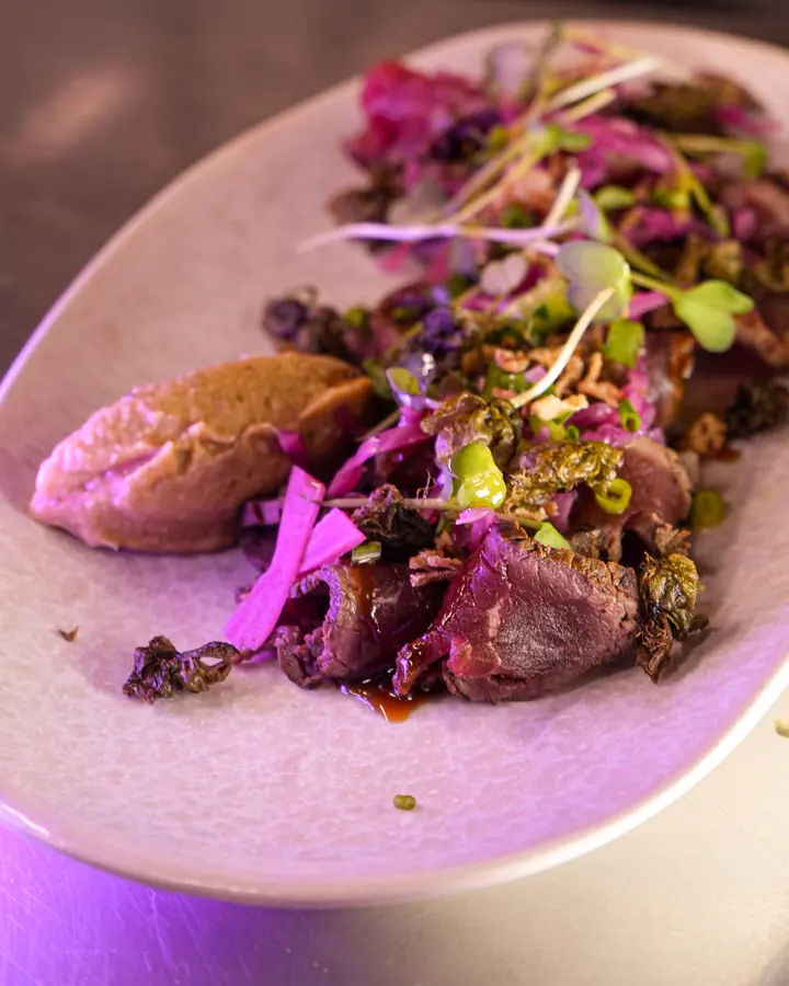 Une assiette à partager : viande tranchée, purée, chou rouge et jeunes pousses