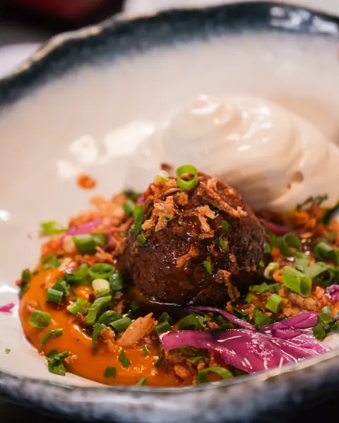 Boulette croustillante sur purée orangée, chou rouge et crème fouettée