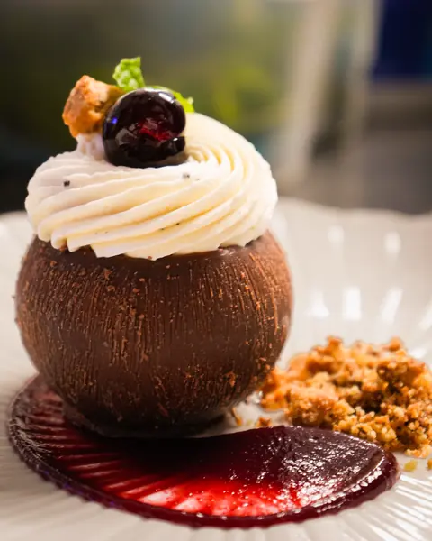 Sphère en chocolat, chantilly, cerise, crumble et coulis rouge