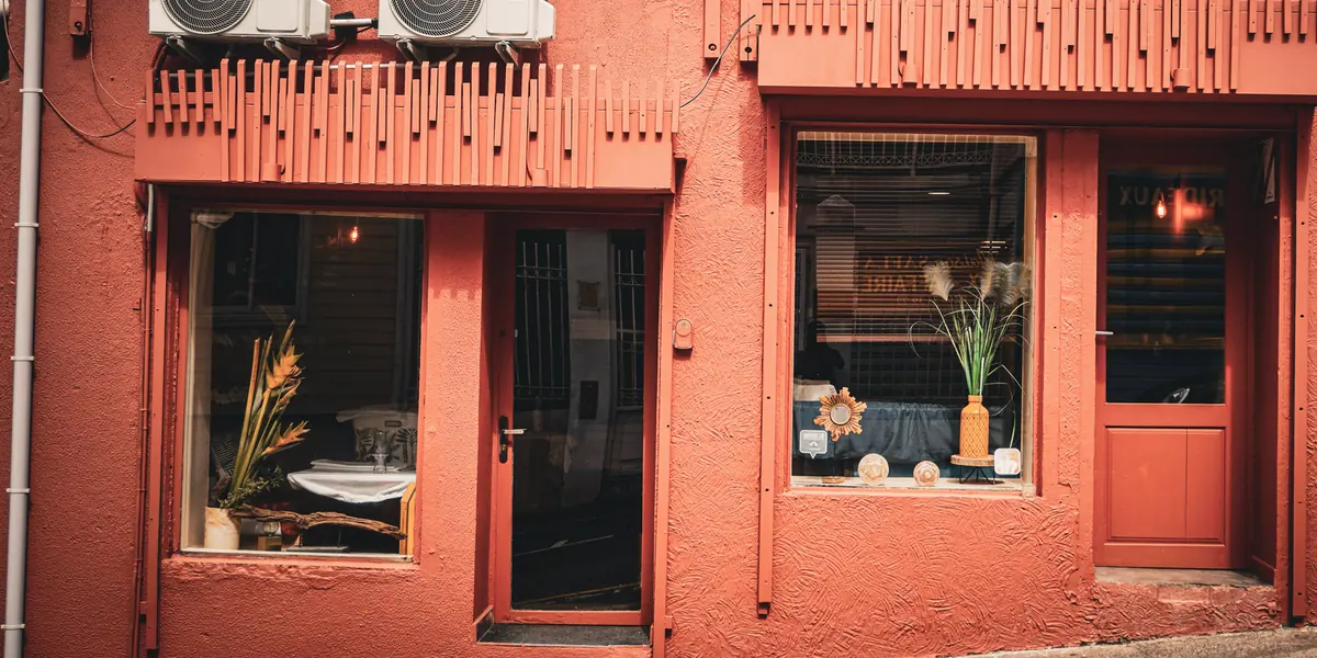 La façade terracotta, ses lambrequins de bois corail et ses deux vitrines